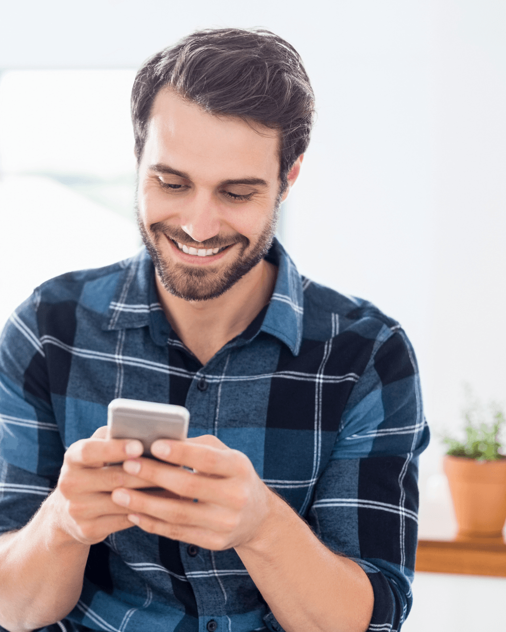 Hombre sonriendo mientras usa su teléfono móvil